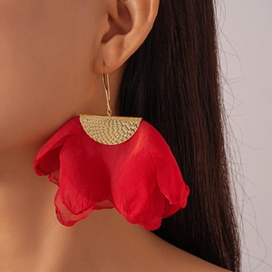 Detail view of red fabric petal earrings with golden brushed metal finish on model