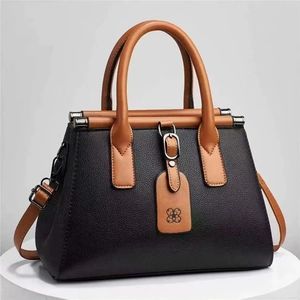 Elegant black lychee pattern handbag with tan handles and decorative flower charm