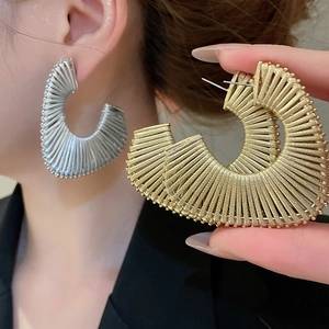 Detailed view of silver and gold C-shaped earrings with textured stripe design
