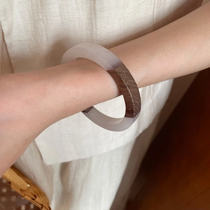 Detail of creative resin and wood grain patchwork bangle worn on a female wrist