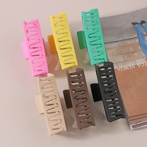Close-up of 13cm matte rectangular hair claw clips in six varied colors on a magazine