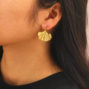 Détail macro de boucles d'oreilles feuille de ginkgo dorées avec textures de veines