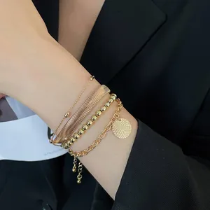 Dettaglio del set di quattro bracciali dorati con catene a serpente e ciondolo rotondo
