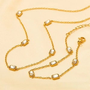 Detailed shot of gold plated necklace set with rectangular zircon on beige silk cloth