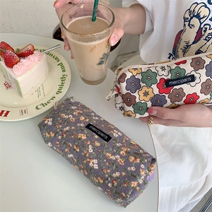 Detail of vintage corduroy floral pencil case and makeup bag on a cafe table