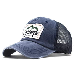 Close-up of distressed navy explorer cap with embroidered mountain patch and black mesh back