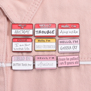 Detailed view of nine colorful metal name tag pins with funny text on pink denim fabric