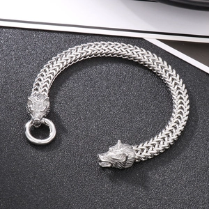 Detailed macro of double-row woven chain bracelet featuring carved twin wolf heads