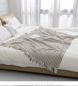Detail view of the beige striped knit throw blanket with soft decorative tassels