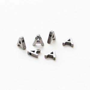 Macro view of six silver-tone metal letter A beads with 1.8mm holes for DIY jewelry