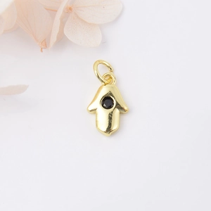Macro detail of golden Hamsa hand pendant with a central black gemstone and clasp