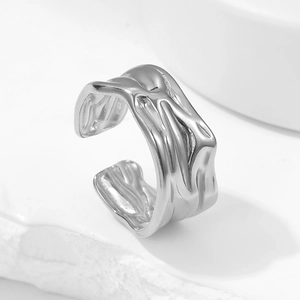 Minimalist liquid metal style open ring in silver finish on white stone background