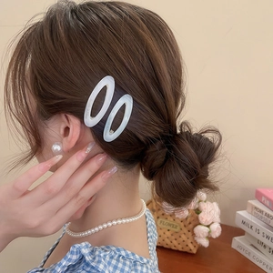 Close-up of pearl white acetate oval hair clips worn as side pins on a female model
