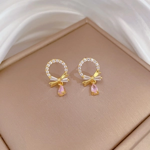 Detail of gold drop earrings with pink zircon waterdrop and white crystals on silk