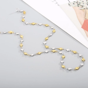 Detailed view of heart-shaped links in gold and silver stainless steel chain necklace