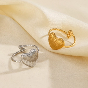 Minimalist 18K gold and silver heart rings on satin fabric with textured metal details