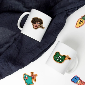 Close-up of colorful cartoon monster stickers on a white ceramic mug with blue knit background