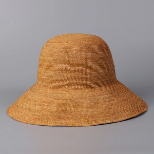 Macro shot of tightly hand-woven caramel raffia straw pattern on wide brim sun hat
