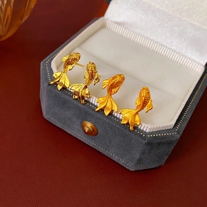Boucles d'oreilles carpe koï dorées avec texture mate et détails en relief sur écrin