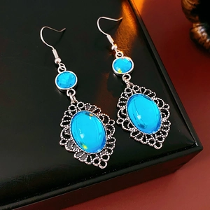 Detailed close-up of vintage silver oval blue resin drop earrings with intricate patterns