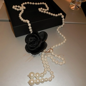 Detail einer perlenkette mit schwarzer Kamelie auf einer luxuriösen Geschenkbox