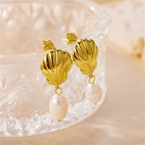 French style gold shell earrings with elegant oval white pearls on a glass bowl