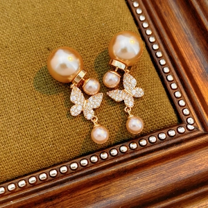 Macro detail of vintage gold-plated butterfly earrings with double pearls and zircons