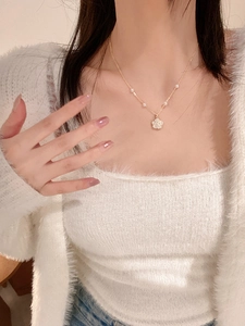 Detail of a floral pearl necklace with gold finish worn by a model in soft lighting