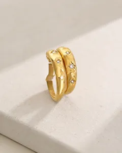 Detailansicht goldener Schichtringe mit Gravuren in Sternform und weißen Kristallen