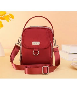 Detail of red nylon crossbody bag with multi-layer zipper pockets and silver hardware
