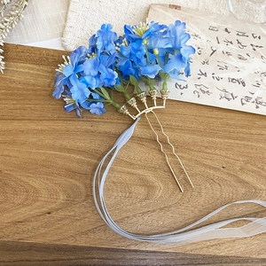 Macro detail of blue silk flowers and long chiffon tassels on a gold metal hair pin