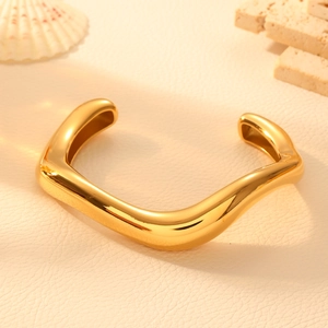 Minimalist gold wave stainless steel open bangle with a polished mirror finish on stone