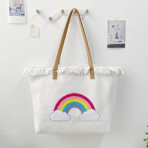 Detail of white woven tote bag with rainbow pattern, white tassels and brown leather handles