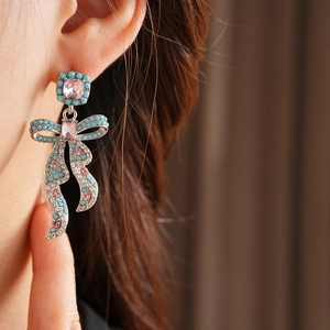 Gros plan de boucles d'oreilles nœud vintage avec gemme rose et perles turquoise