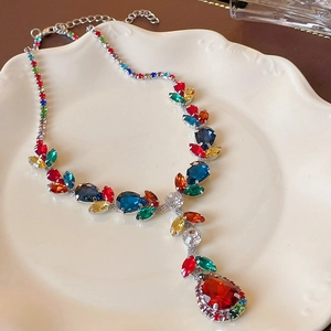Macro detail of leaf-shaped design and teardrop red zircon on luxury necklace