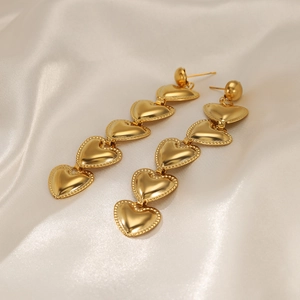 Elegant gold-plated heart drop earrings with five tiered hearts on a white silk background
