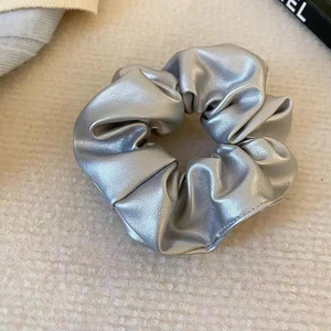Detailed close-up of metallic silver faux leather scrunchie with pleated texture