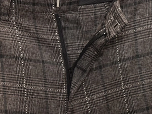 Gros plan sur la braguette zippée et la taille du pantalon en laine à carreaux