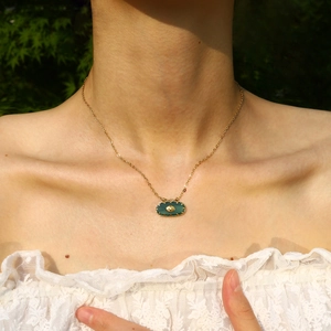 Collier vintage en acier inoxydable doré 18K avec pendentif ovale vert porté par modèle
