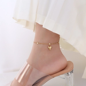 18k gold plated heart anklet with zircons on model wearing white pleated skirt