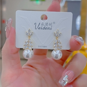 Detailed view of long tassel earrings with marquise zircon leaves and white pearls