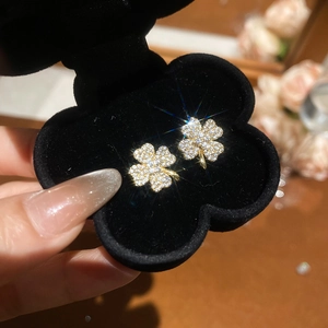 Detailed macro view of gold-plated clover earrings inlaid with sparkling white zircons