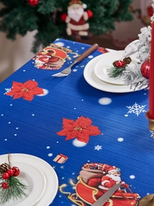 Detail of Christmas tablecloth featuring festive reindeer, florals, and textured blue fabric