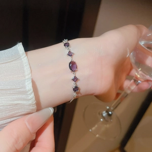 Detail of elegant silver bracelet with oval purple gemstones on a woman's wrist