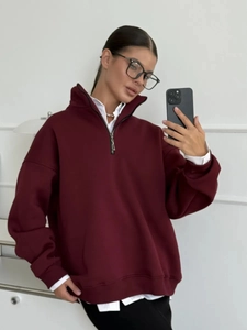 Macro shot of oversized burgundy sweatshirt featuring a half-zip stand collar and thick knit
