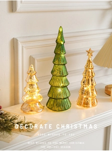 Close-up of three lighted mercury glass Christmas trees on a white mantel fireplace