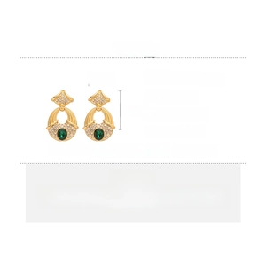 Vue macro de boucles d'oreilles dorées vintage avec gemmes vertes et strass