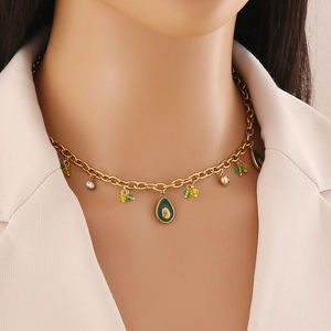 Close-up of model wearing gold chain necklace with green crystal fruit pendants