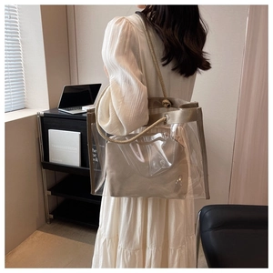 Detailed side view of a transparent PVC tote bag with a beige inner pouch and rope handles