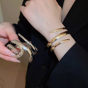 Close-up of golden and silver spiral layered open cuff bracelet with mirror finish